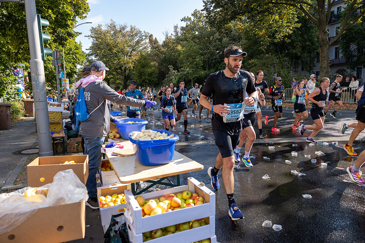  BMW BERLIN-MARATHON 2023: Läufer:innen erhalten an der Verpflegungsstation Obst © SCC EVENTS / Norbert Wilhelmi